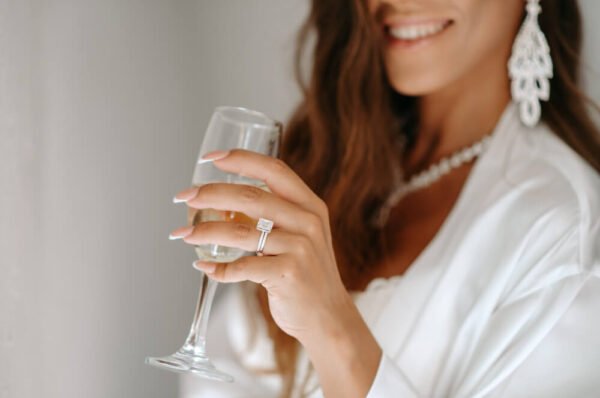 A close-up of a woman's hand holding a glass of champagne, with a diamond bracelet on her wrist