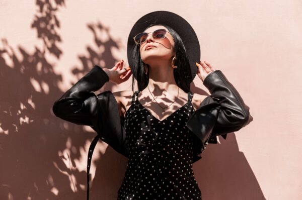 fresh-portrait-sexy-young-woman-elegant-hat-beautiful-dress-fashionable-sunglasses-leather-black-jacket-near-pink-wall-shade-tree-lovely-girl-trendy-outfit-enjoys-min (1)