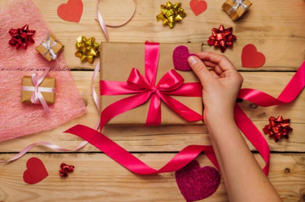 holiday gift ideas womens-hands-hold-gift-box-wooden-background-concept-valentines-day-mothers-day